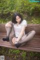 A woman sitting on a wooden bench in a park.