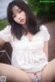 A woman in a white shirt and panties sitting on a bench.