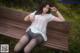 A woman sitting on a wooden bench in the grass.