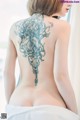 A woman with a tattoo on her back is wrapped in a towel.