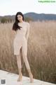 A woman in a beige sweater dress standing on a wooden boardwalk.