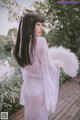 A woman in a white kimono holding a white fan.