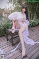 A woman sitting on a wooden bench holding a fan.