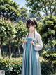 A woman in a blue and white dress standing in a garden.