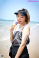 A woman eating an ice cream cone on the beach.