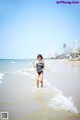 A woman in a bathing suit running on the beach.