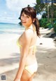 A woman in a yellow bikini standing on a beach.