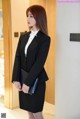 A woman in a black suit standing in a hallway.