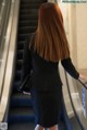 A woman in a business suit is walking down an escalator.