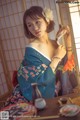 A woman in a blue kimono sitting at a table.