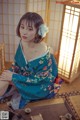 A woman in a blue kimono sitting on the floor.