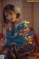 A woman in a blue kimono sitting on a table.