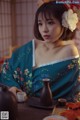 A woman in a blue kimono sitting at a table.