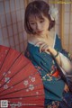 A woman in a kimono holding a red umbrella.