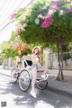 A woman sitting on the back of a rickshaw on a city street.