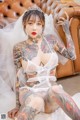 A woman with tattoos sitting on a couch wearing a wedding dress.