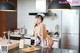 A woman in a maid outfit is preparing food in the kitchen.