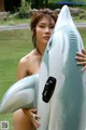 A woman holding a large inflatable shark in the water.