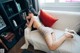 A woman laying on a white couch with a red pillow.