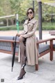 A woman sitting on a bench holding an umbrella.