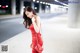 A woman in a red dress is walking down the street.