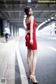 A woman in a red dress is standing on the street.