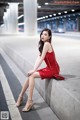 A woman in a red dress sitting on a concrete ledge.