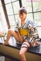 A woman in a kimono sitting on a window sill.