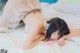 A woman laying on a bed with a pink toy in her mouth.