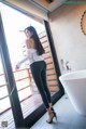 A woman standing in front of a bathtub in a bathroom.