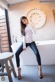 A woman sitting on a stool in a bathroom.