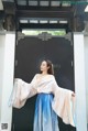 A woman in a blue and white dress standing in front of a door.