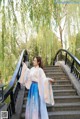 A woman in a blue and pink dress standing on a bridge.