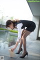 A woman in a black skirt and white shirt is bending over to pick up a book.