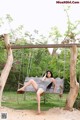 A woman sitting on a swing in a park.