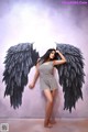 A woman standing in front of a wall with black angel wings.