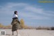 A woman standing in the middle of a sandy field.