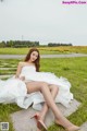 A woman in a white dress sitting on the grass.